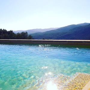 Montnegre的住宿－Mas Oms，一座大池的蓝色海水,背景是群山