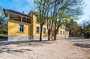 ein gelbes Haus mit Bäumen davor in der Unterkunft Villa Aurum Health & Climatotherapy Center in Rovinj