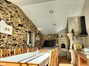 Casa Os Lindeiros ! Casa con PISCINA en Arzúa في أرزوا: مطبخ مع طاولة وجدار حجري
