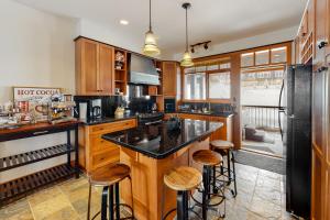 Una cocina con gabinetes de madera y taburetes de bar. en Blacksmith Lodge 4, en Big White