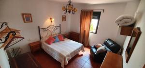 1 dormitorio con 1 cama y 1 silla en Tu Casa Rural, en Castilblanco de los Arroyos