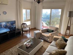 - un salon avec un canapé et une télévision dans l'établissement Nile View Apartment in Zamalek Stays, au Caire