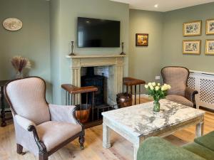 a living room with a fireplace and a table and chairs at Converted Victorian Coach House with Hot Tub in Stewartstown