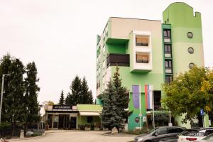 MC Hotel في Žalec: مبنى أخضر فيه سيارات متوقفة أمامه