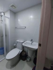 een witte badkamer met een toilet en een wastafel bij Minimalist Loft 107 in Baguio