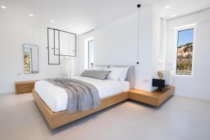 a white bedroom with a large bed and a window at ISTIA LUXURY VILLAS in Karpathos