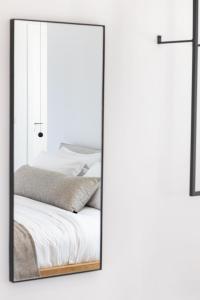 a mirror hanging on a wall next to a bed at ISTIA LUXURY VILLAS in Karpathos Town