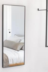 uno specchio appeso a un muro accanto a un letto di ISTIA LUXURY VILLAS a Karpathos