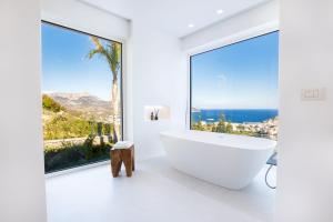 a white bathroom with a tub and a large window at ISTIA LUXURY VILLAS in Karpathos Town