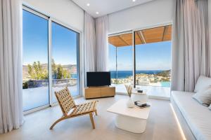 a living room with a couch and a tv and large windows at ISTIA LUXURY VILLAS in Karpathos Town +102 photos