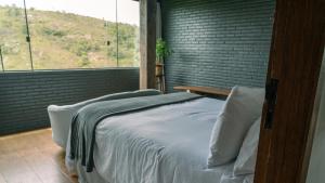 a bed in a room with a large window at Pousada Monttana in Lavras Novas