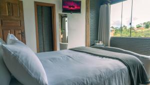 a bedroom with a large bed with a window at Pousada Monttana in Lavras Novas