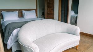 a bedroom with a bed and a white chair at Pousada Monttana in Lavras Novas