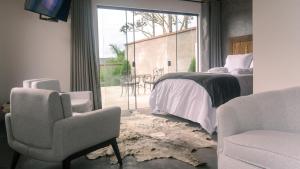 a bedroom with a bed and two chairs and a window at Pousada Monttana in Lavras Novas