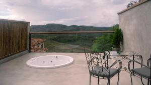 a balcony with a hot tub and chairs and a view at Pousada Monttana in Lavras Novas