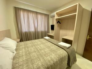 a hotel room with a bed and a window at Residencial Shalfa in Foz do Iguaçu