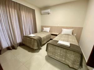 a hotel room with two beds and a window at Residencial Shalfa in Foz do Iguaçu