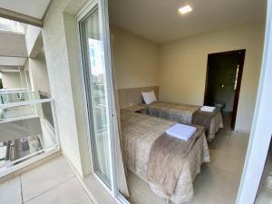 a hotel room with two beds and a balcony at Residencial Shalfa in Foz do Iguaçu