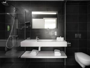 bagno con lavandino, specchio e servizi igienici di Le 24 Hotel a Spa