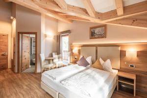 una camera da letto con un grande letto bianco e soffitti in legno di Albergo Belvedere a Vigo di Fassa