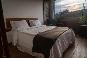 a bedroom with a bed and a chair and a window at Pousada Monttana in Lavras Novas