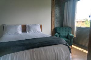 a bedroom with a bed and a green chair at Pousada Monttana in Lavras Novas