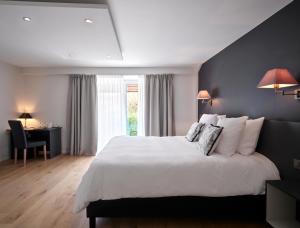 a bedroom with a large white bed and a desk at Le 24 Hotel in Spa