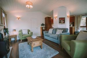 a living room with two couches and a table at Walled Garden Lodges Loch Lomond in Balloch
