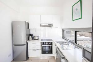 La cuisine blanche est équipée d'un réfrigérateur et d'un évier. dans l'établissement Villa Trianta, à Neo Chorio