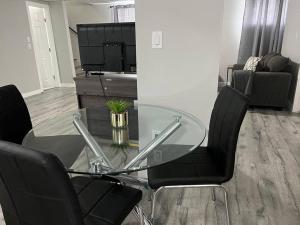 una mesa de cristal y 2 sillas negras en la sala de estar. en Cozy Modern and Lavish 2 Bedroom Basement Suite, en Winnipeg