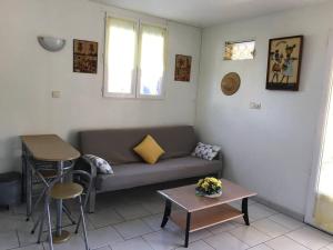 ein Wohnzimmer mit einem Sofa und einem Tisch in der Unterkunft Studio proche mer & climatisé les Anses d'Arlet in Les Anses-dʼArlets