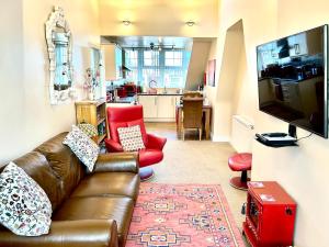 a living room with a brown leather couch and red chairs at The Upper Bakery in Cromer