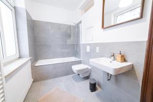 a bathroom with a sink and a toilet and a bath tub at FULL HOUSE 3 Bedroom Apartment Halle NH14 in Halle an der Saale