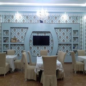 une salle à manger avec des tables, des chaises et une télévision dans l'établissement UYUT INN Hotel, à Samarcande