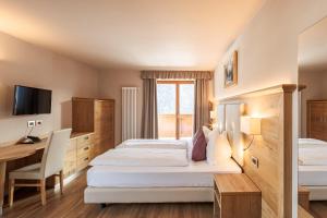 a hotel room with two beds and a desk at Albergo Belvedere in Vigo di Fassa