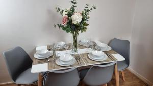 a table with chairs and a vase of flowers on it at The Pearl of Greenwich - Two bedroom flat next to Cutty Sark in London