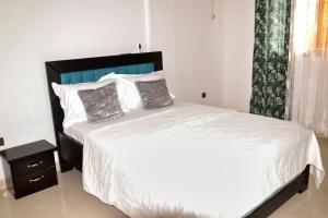 a bedroom with a white bed and a window at Tulsa Home - Douala - Bonamoussadi - Wifi - Canal+ in Douala