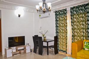 a living room with a dining table and a television at Tulsa Home - Douala - Bonamoussadi - Wifi - Canal+ in Douala