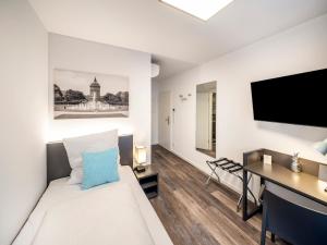 Zimmer mit einem Bett, einem Schreibtisch und einem TV in der Unterkunft Boarding World smart Hotel in Mannheim