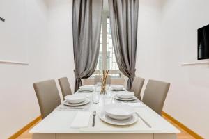 a dining room table with chairs and white dishes on it at Vatican Prestige Apt by Premium Suites Collection in Rome