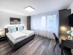 Schlafzimmer mit einem Bett, einem Schreibtisch und einem Fenster in der Unterkunft Boarding World smart Hotel in Mannheim