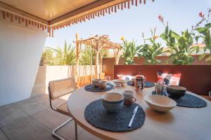 - une table avec des bols et des assiettes sur la terrasse dans l'établissement Villa Ananda - Chandra - Un havre de paix entre mer et étangs, à Carnon-Plage