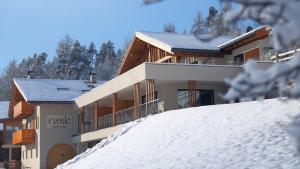 a house on top of a snow covered hill at Runk Apartments in Siusi