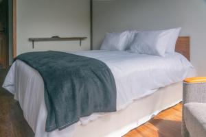 a white bed with a green blanket on it at Pousada Monttana in Lavras Novas