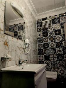 y baño con lavabo y azulejos blancos y negros. en Hotel Anibal, en Gebze