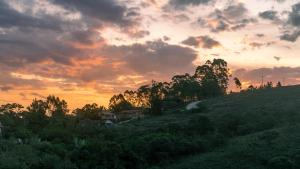 a sunset over a field with a house on a hill at Pousada Monttana in Lavras Novas