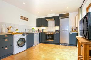 a kitchen with blue cabinets and a washer and dryer at Beautiful City Centre Apartment with Free Parking, Fast-Wifi, SmartTV with Netflix and Private Garden by Yoko Property in Milton Keynes