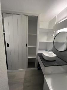 La salle de bains blanche est pourvue d'un lavabo et d'un miroir. dans l'établissement Studio La Mongie, à La Mongie