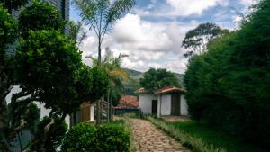 a cobblestone path leading to a house with trees at Pousada Monttana in Lavras Novas