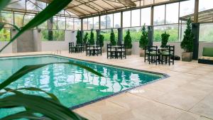 a swimming pool with tables and chairs in a building at Pousada Monttana in Lavras Novas